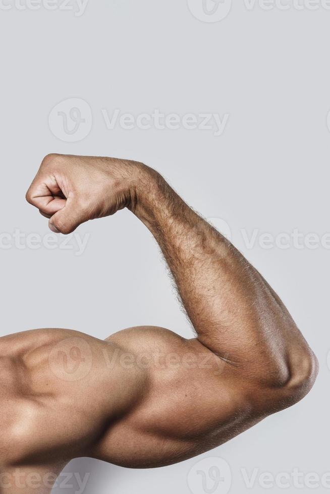 muskulös ärm av ung kroppsbyggare på grå bakgrund foto