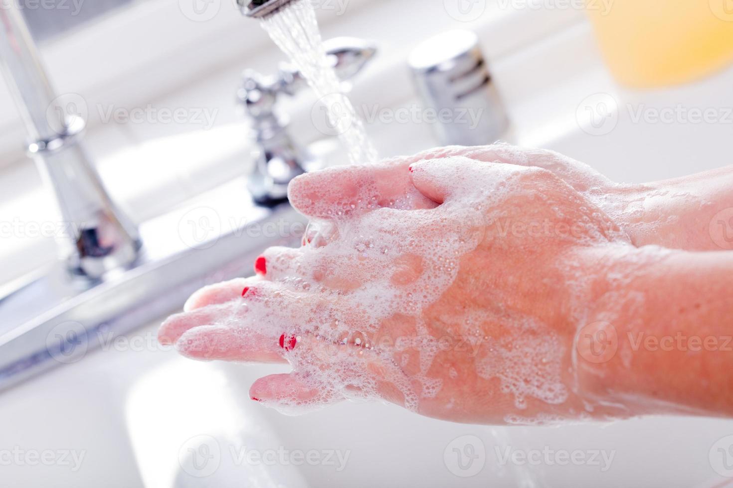 kvinna grundligt tvättning händer i de handfat handfat. foto
