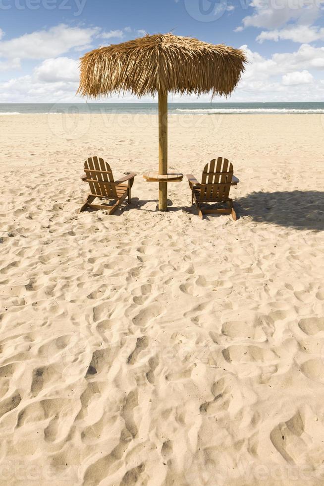 två strand stolar och paraply på skön hav sand foto