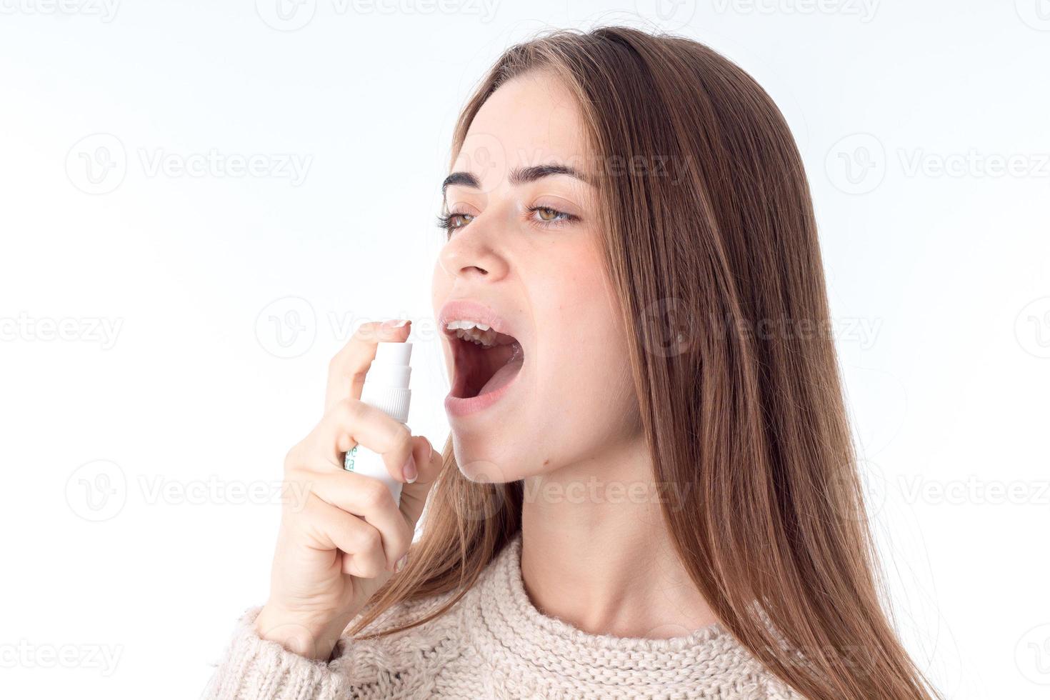 ung flicka innehav en spray för de hals och sprutande närbild foto