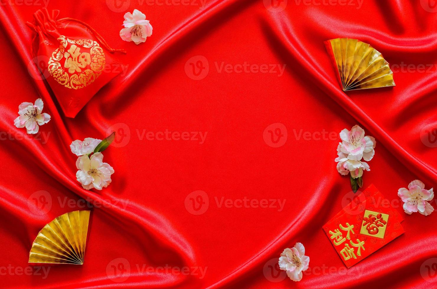 röd satin trasa bakgrund med röd väska ord betyda rikedom och röd kuvert paket eller ang bao ord betyda rikedom, tur- med gyllene fläktar för kinesisk ny år begrepp. foto