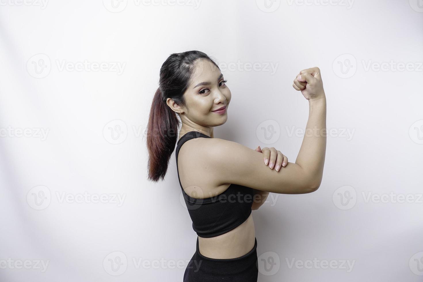 upphetsad asiatisk sportig kvinna bär en sportkläder som visar stark gest förbi lyft henne vapen och muskler leende stolt foto