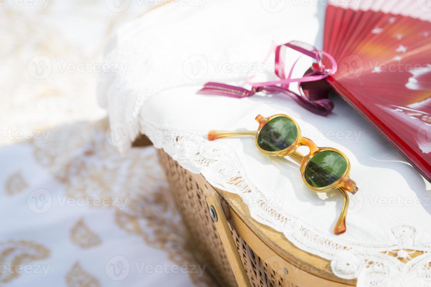 solglasögon, kinesisk fläkt och picknick korg på filt foto