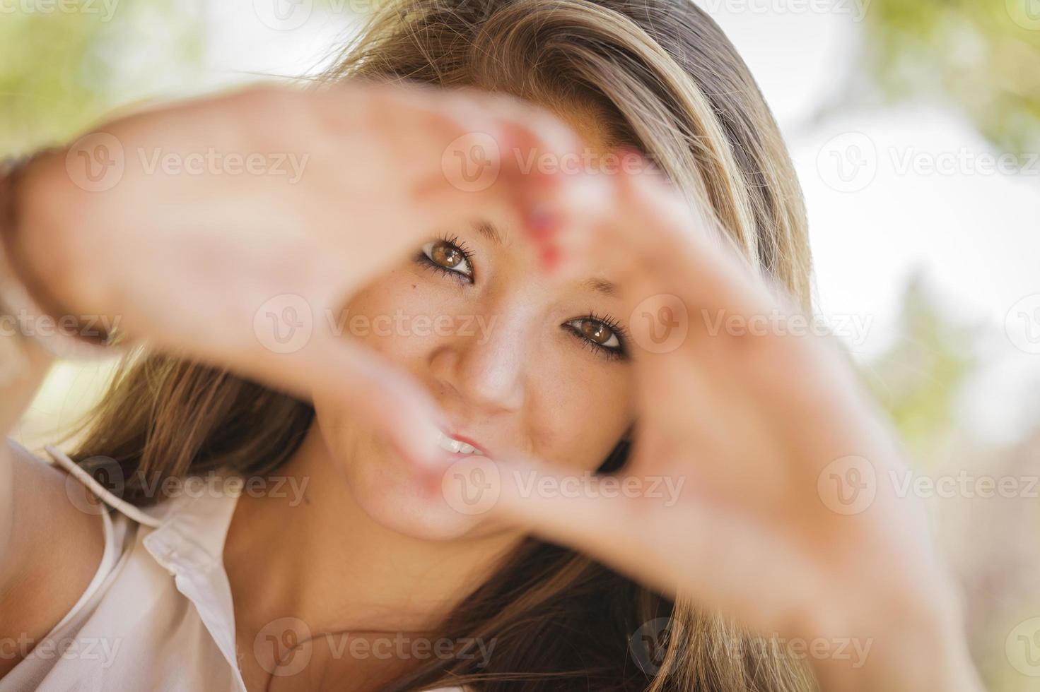 attraktiv leende blandad lopp flicka porträtt med hjärta hand tecken foto