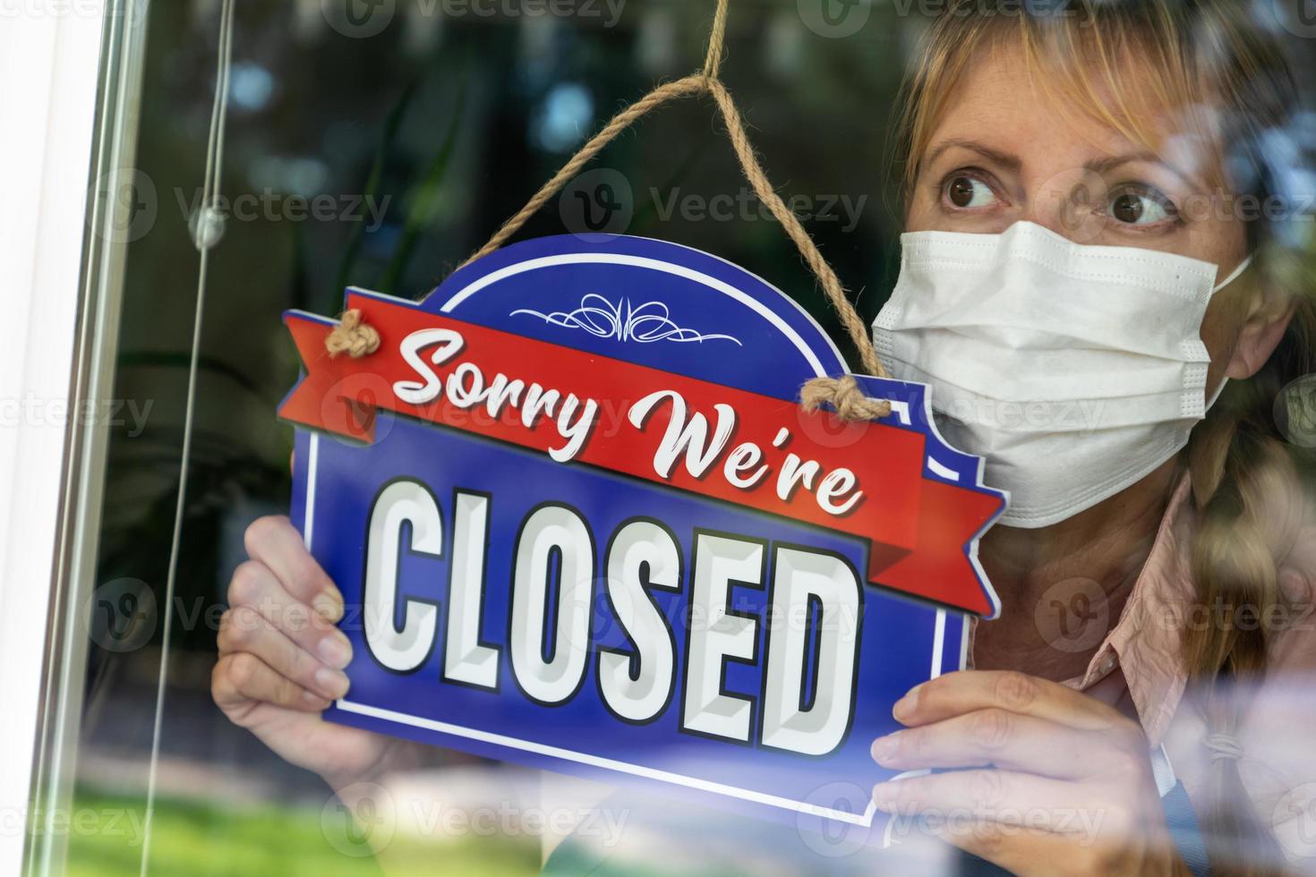 kvinna Lagra ägare bär medicinsk ansikte mask vändning tecken till stängd i fönster foto