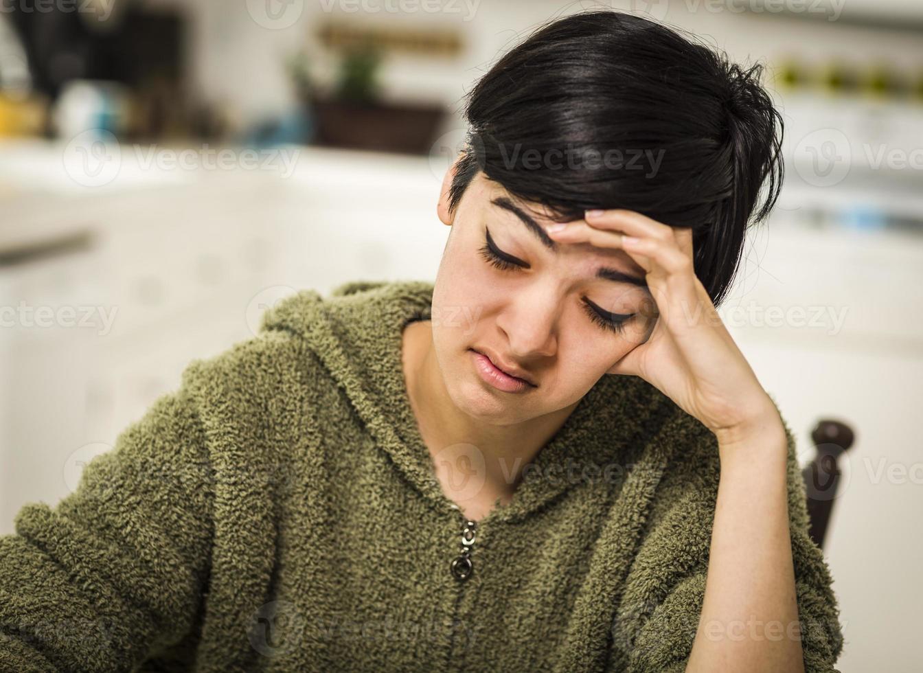 deprimerad blandad lopp ung kvinna Sammanträde ensam i kök foto