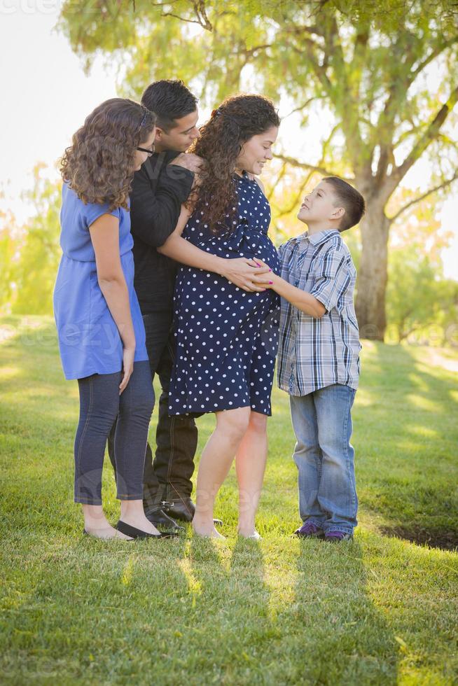 Lycklig attraktiv latinamerikan familj med deras gravid mor utomhus foto