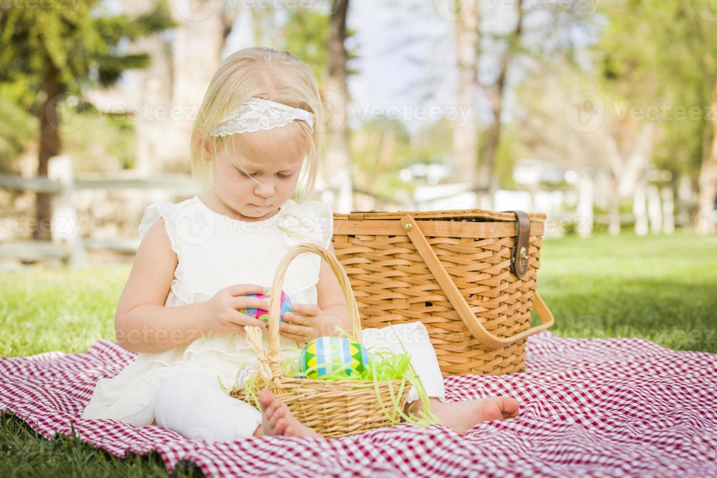 söt bebis flicka njuter henne påsk ägg på picknick filt foto