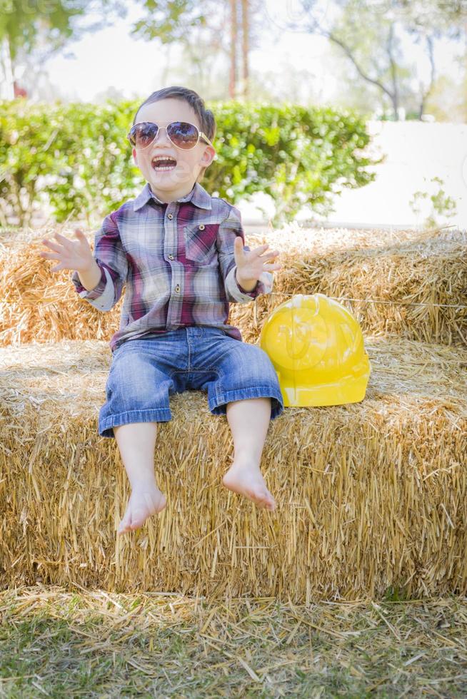 ung blandad lopp pojke skrattande med solglasögon och hård hatt foto