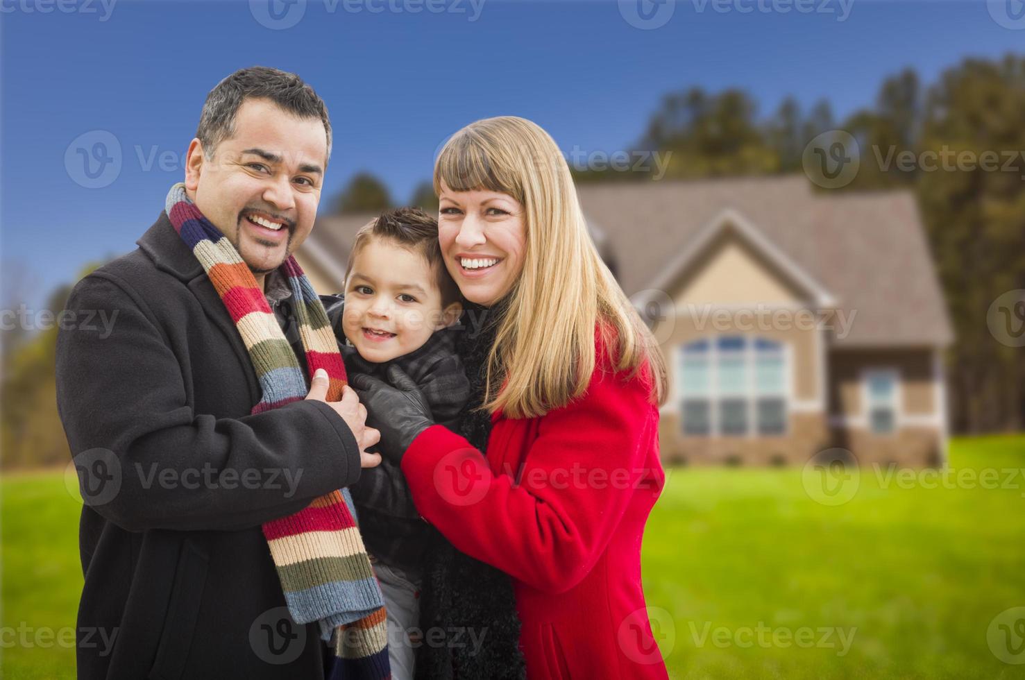 Lycklig blandad lopp familj i främre av hus foto