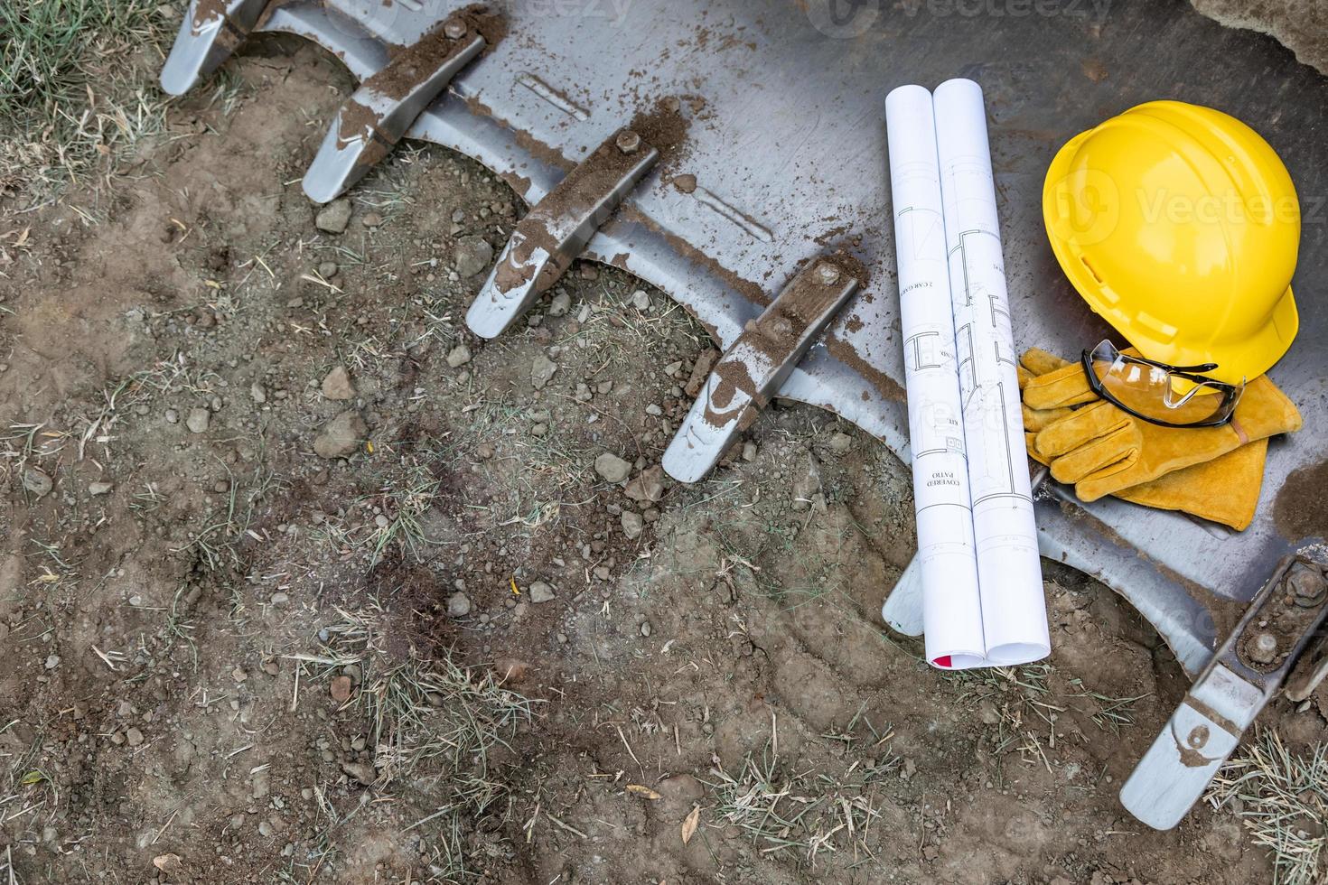 teknisk ritningar, hjälm, handskar och skyddande glasögon vilar på bulldozer hink abstrakt foto