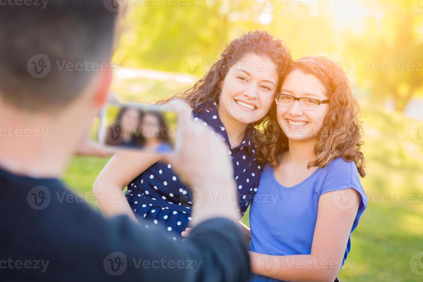 latinamerikan far tar bild av mor och dotter med cell telefon foto