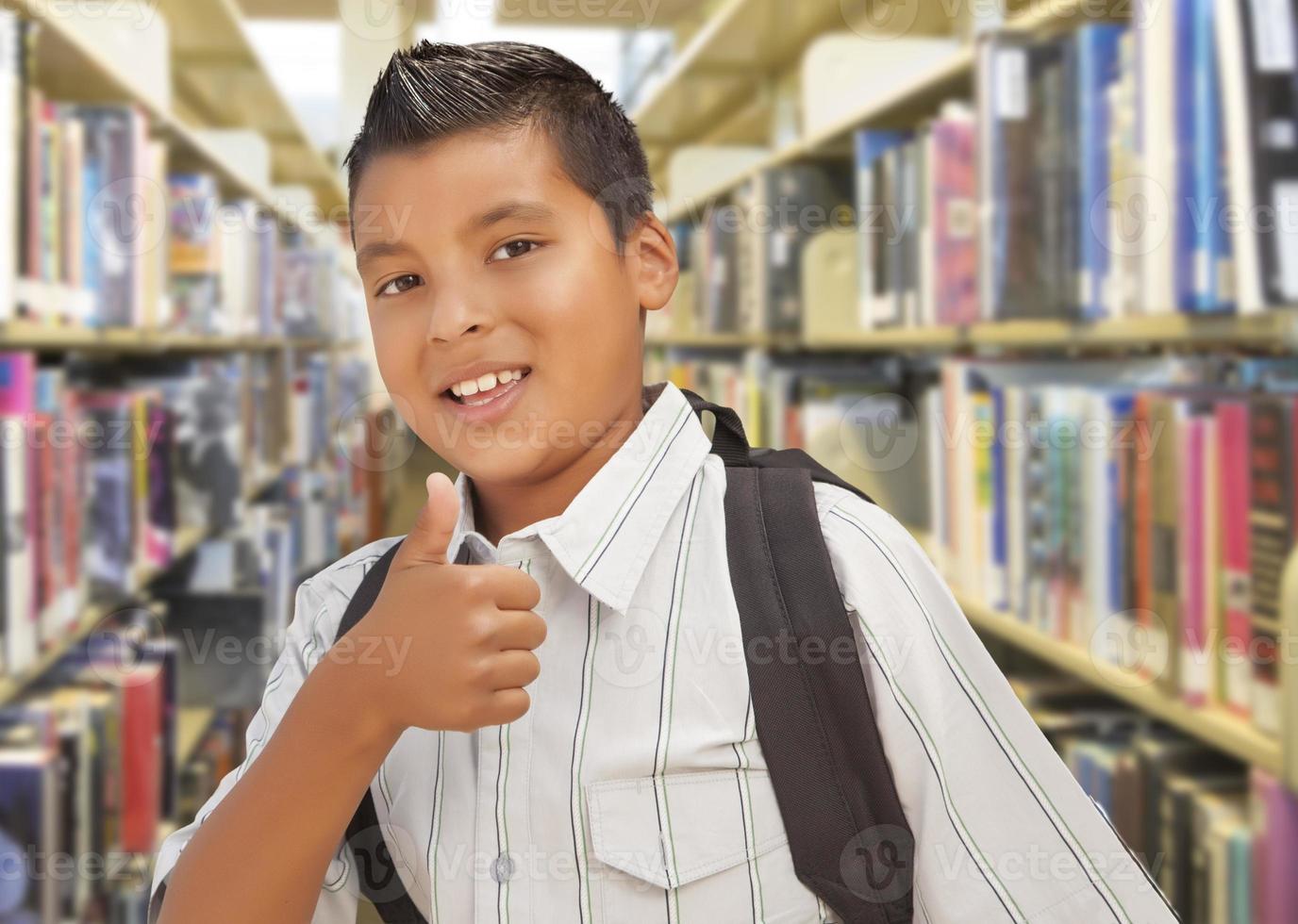 latinamerikan studerande pojke med tummen upp i de bibliotek foto