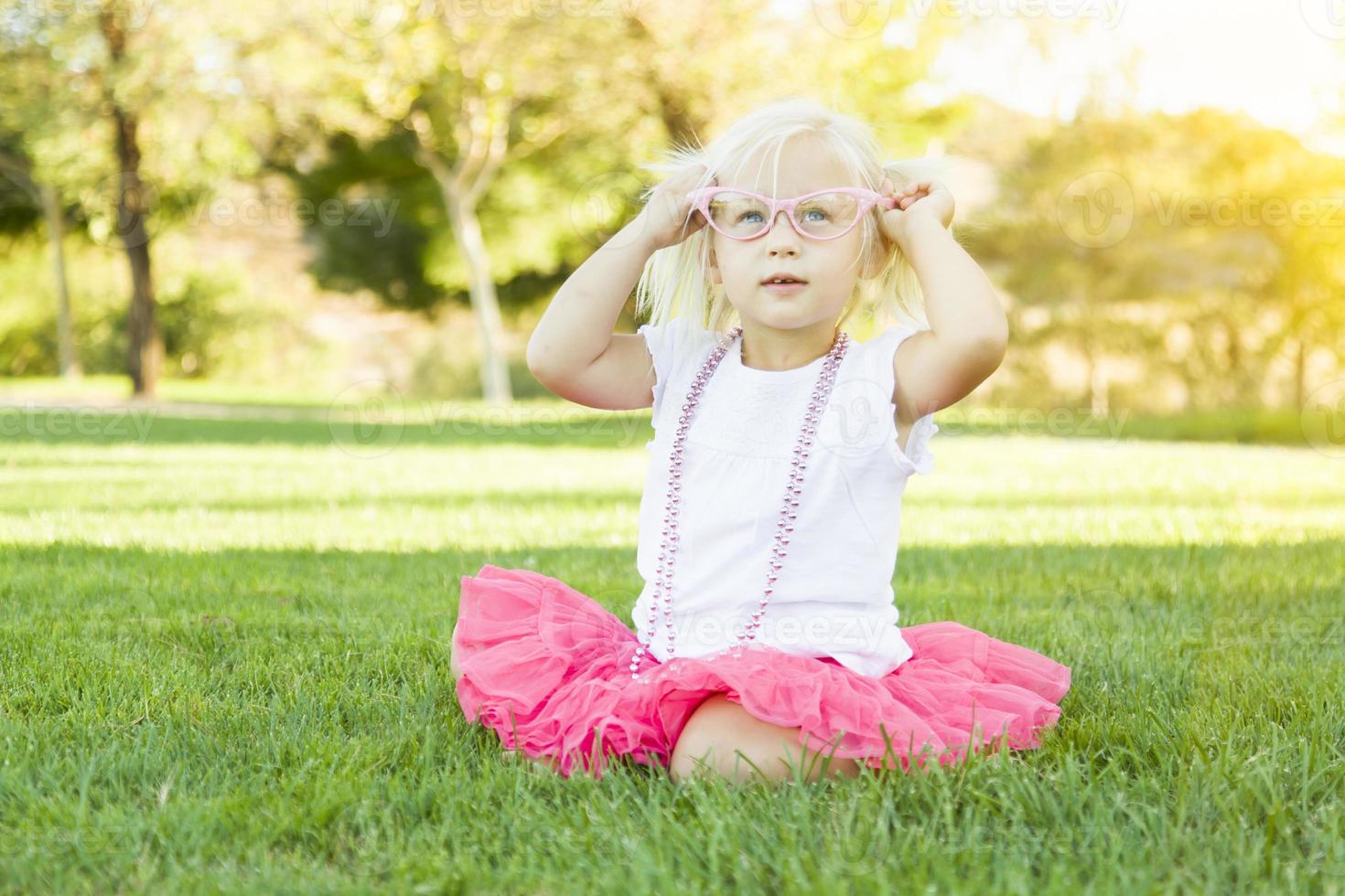 liten flicka spelar klänning upp med rosa glasögon och halsband foto