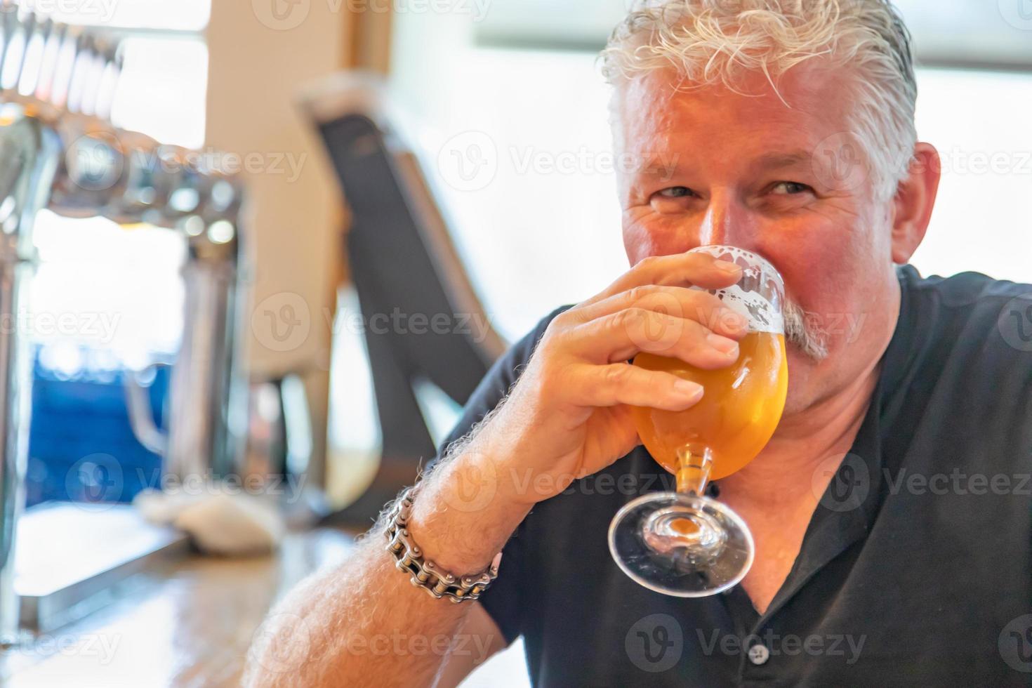 stilig man provsmakning en glas av mikro brygga öl foto