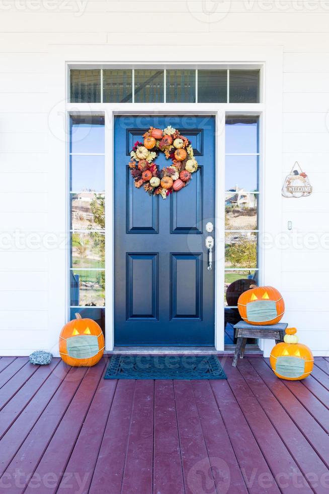 skön hus veranda dekorerad för halloween med pumpor bär medicinsk ansikte masker foto