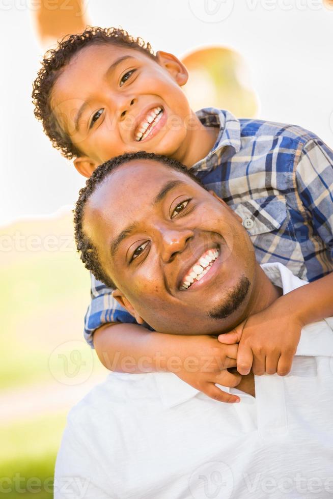 Lycklig afrikansk amerikan far och blandad lopp son spelar på de parkera foto