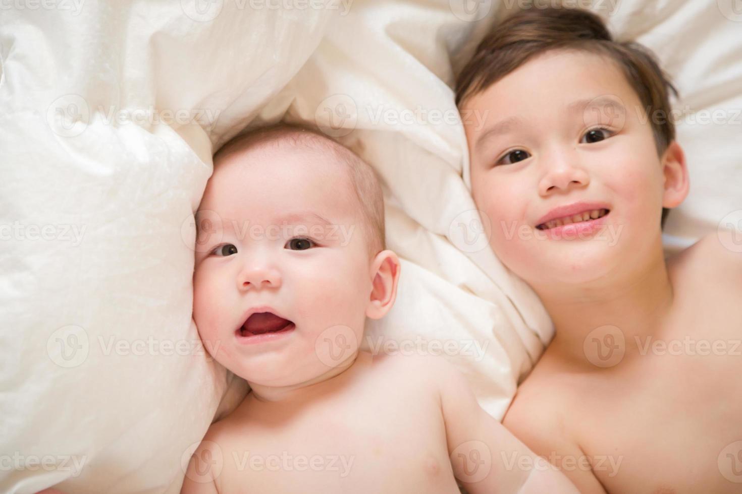 blandad lopp kinesisk och caucasian bebis bröder har roligt om på deras filt foto