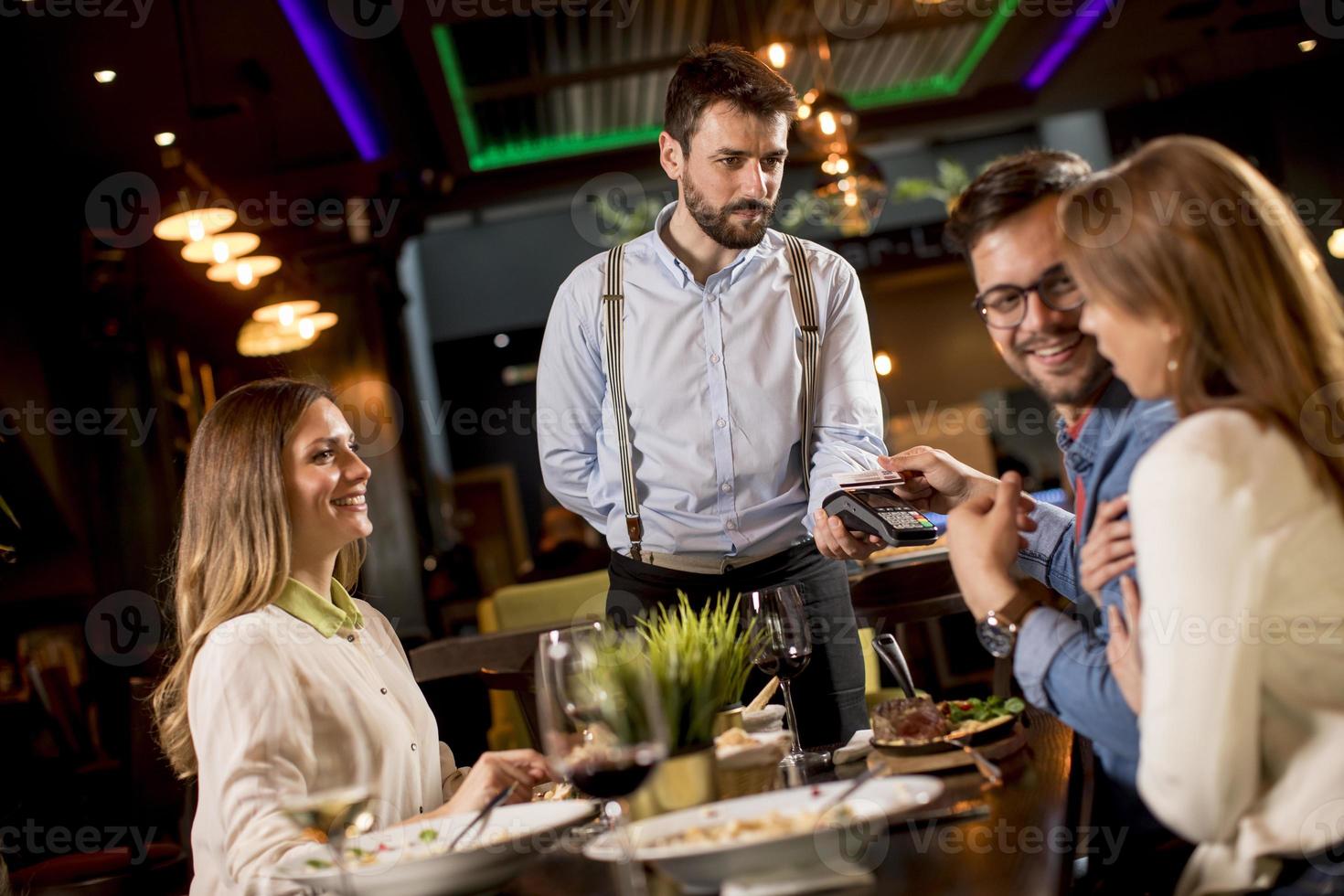 ung man betalande med kontaktlös kreditera kort i de restaurang foto