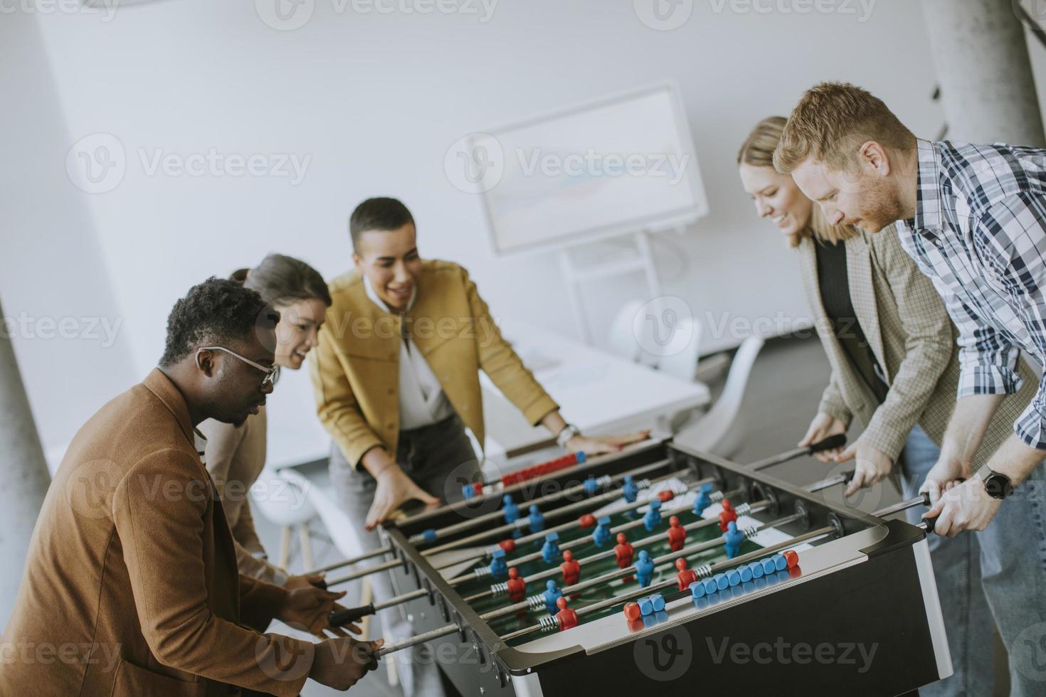 ung tillfällig multietnisk företag människor spelar tabell fotboll och avkopplande på kontor foto