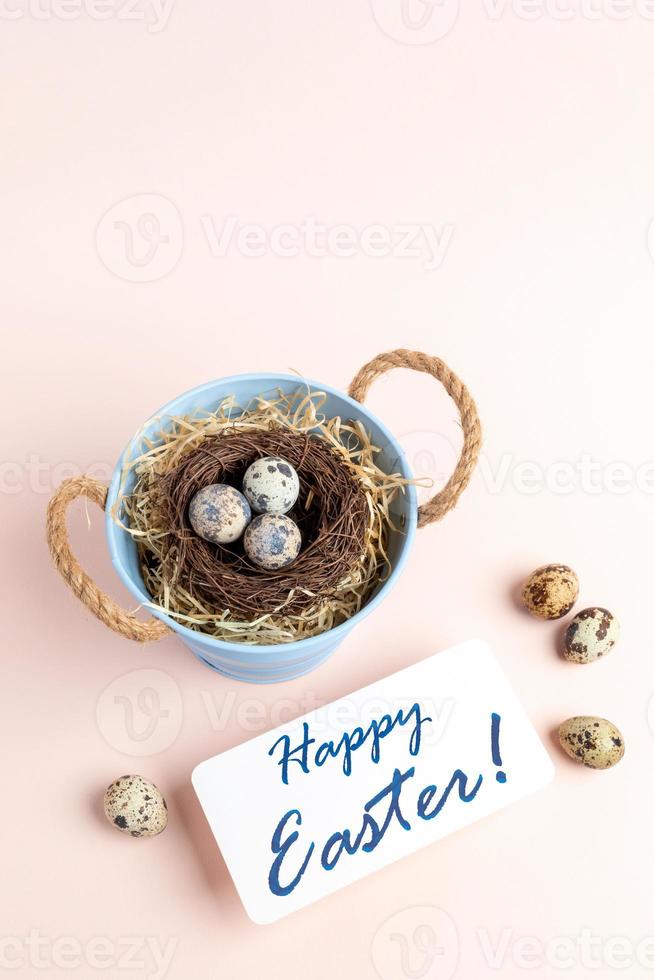 bo av vaktel ägg i små hink, notera Lycklig påsk på pastell rosa vertikal bakgrund. foto