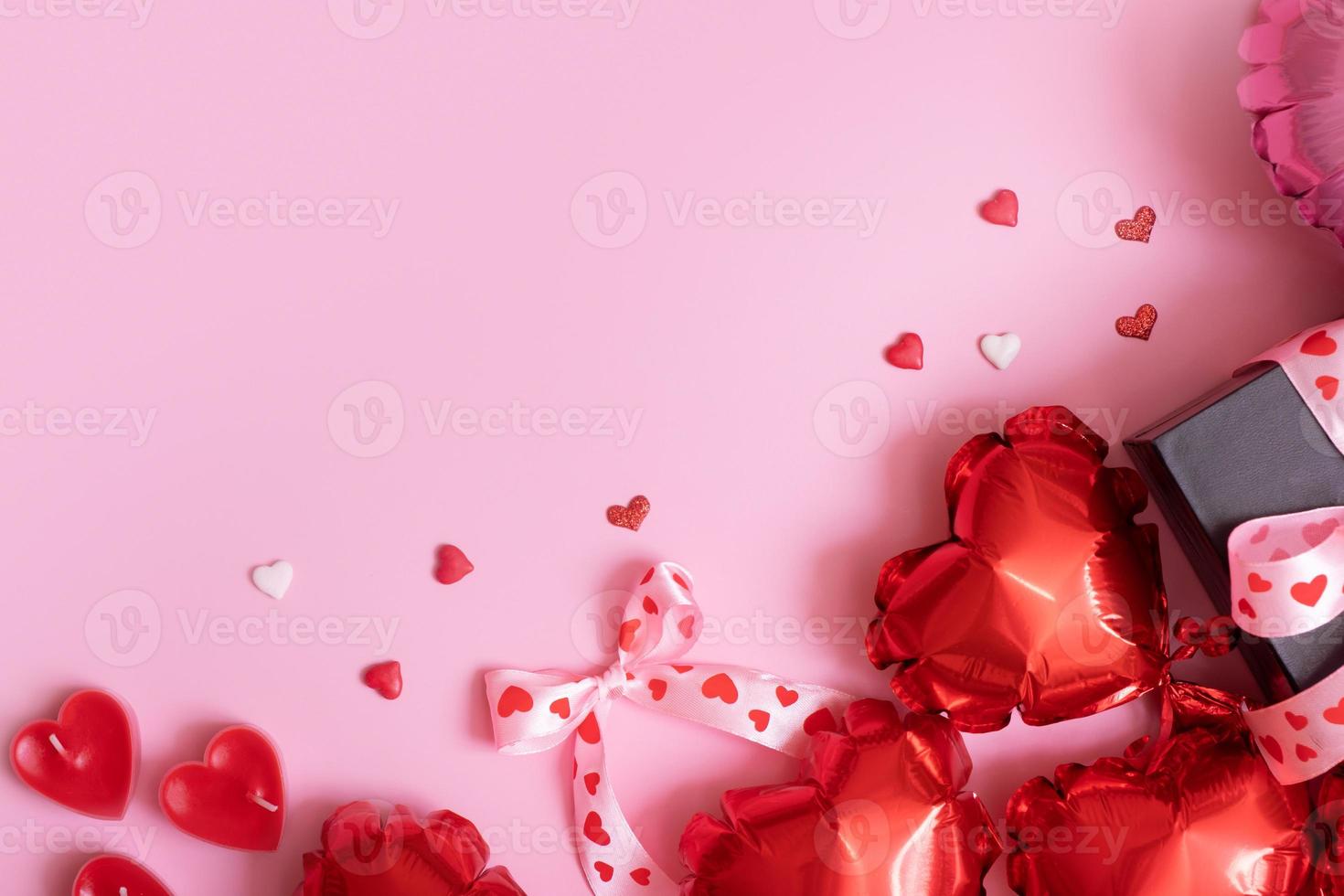 röd hjärta form ballonger, ljus och närvarande låda på rosa bakgrund. valentines dag romantisk bakgrund med kopia Plats foto