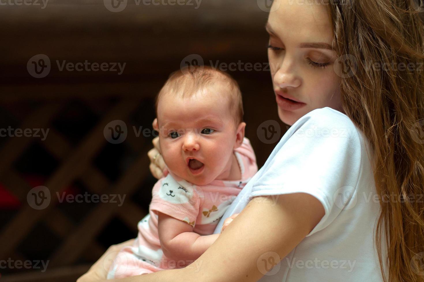 charmig ung mor med liten bebis flicka i händer foto