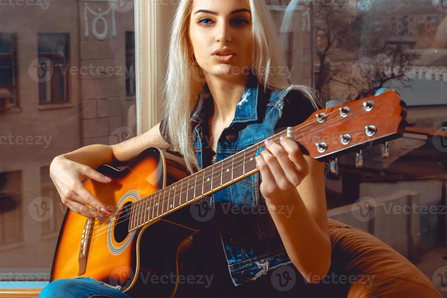 horisontell Foto av ung blond kvinna med gitarr i henne händer
