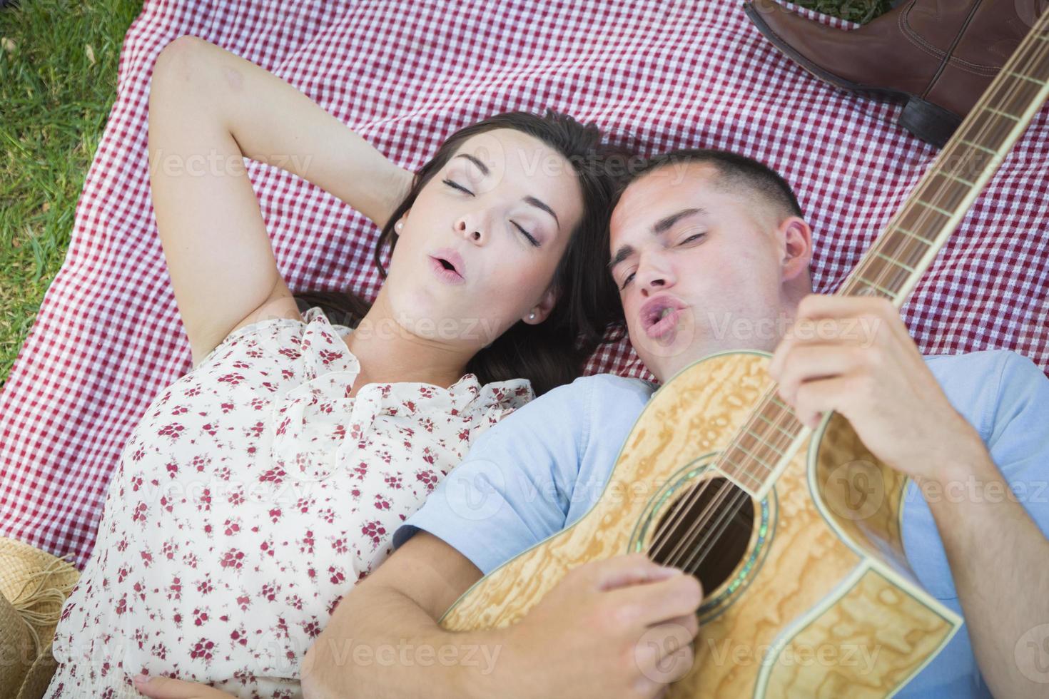 blandad lopp par på de parkera spelar gitarr och sång foto