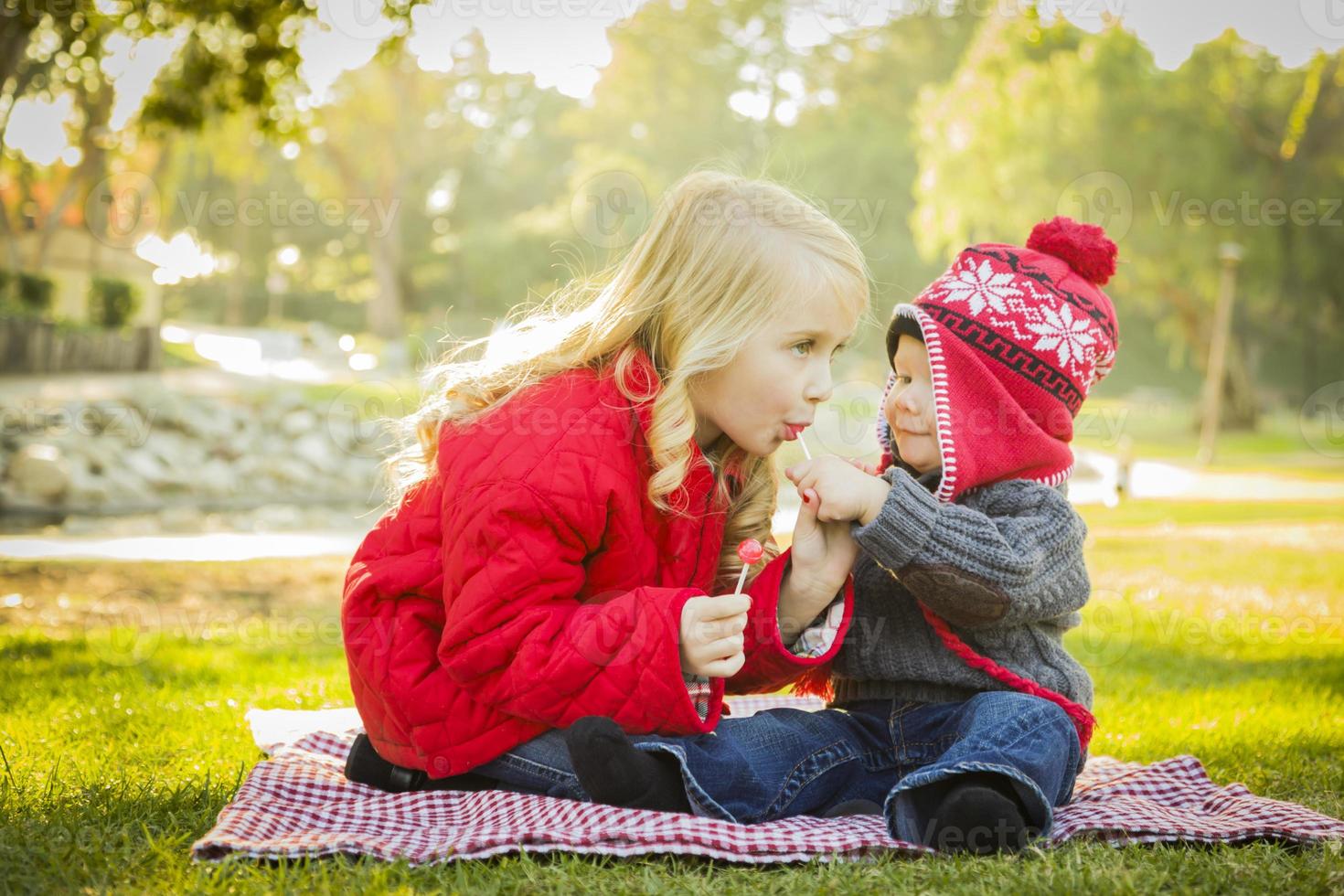 liten flicka med bebis bror bär rockar och hattar utomhus foto