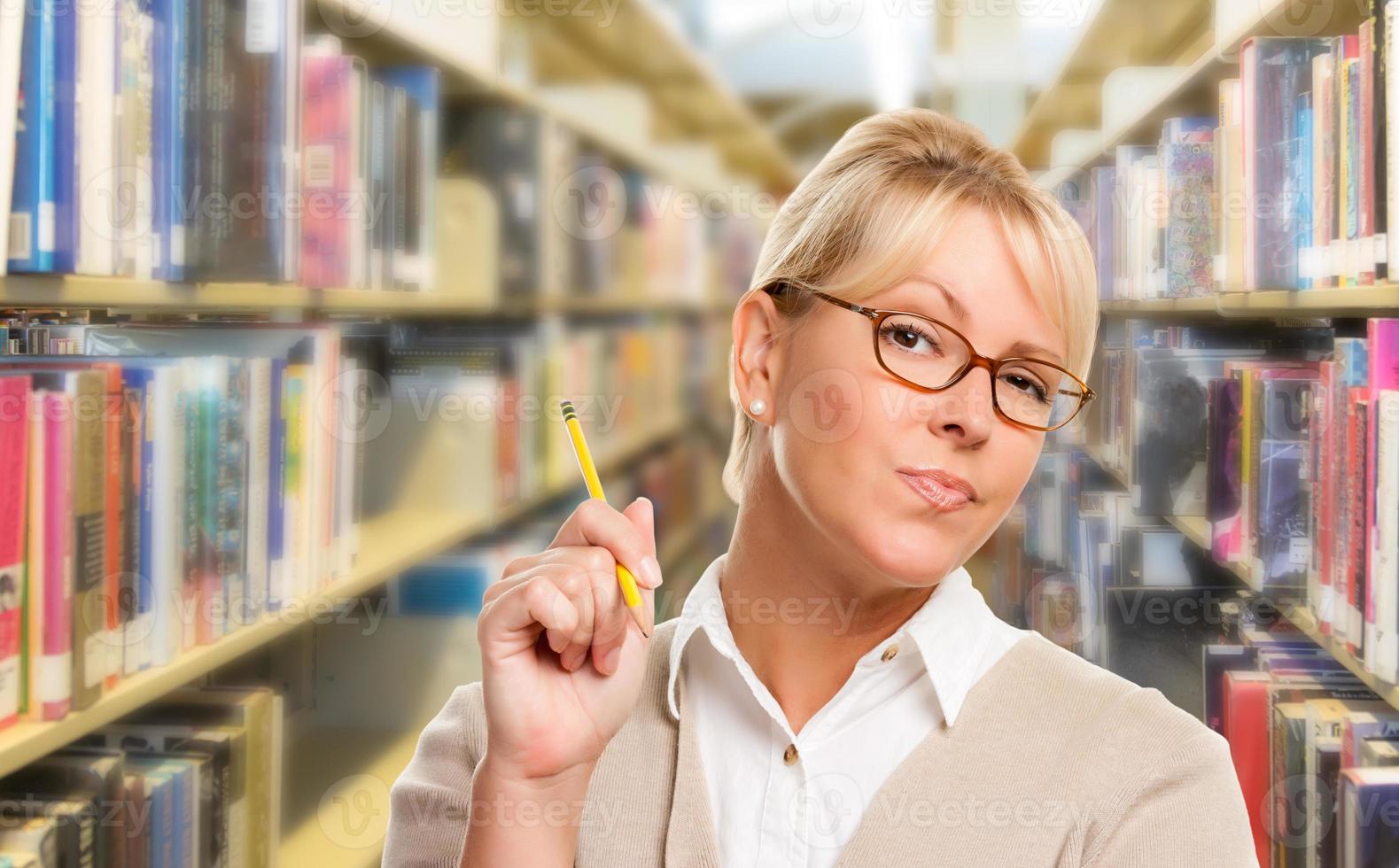 skön uttrycksfull studerande eller lärare med penna i bibliotek. foto