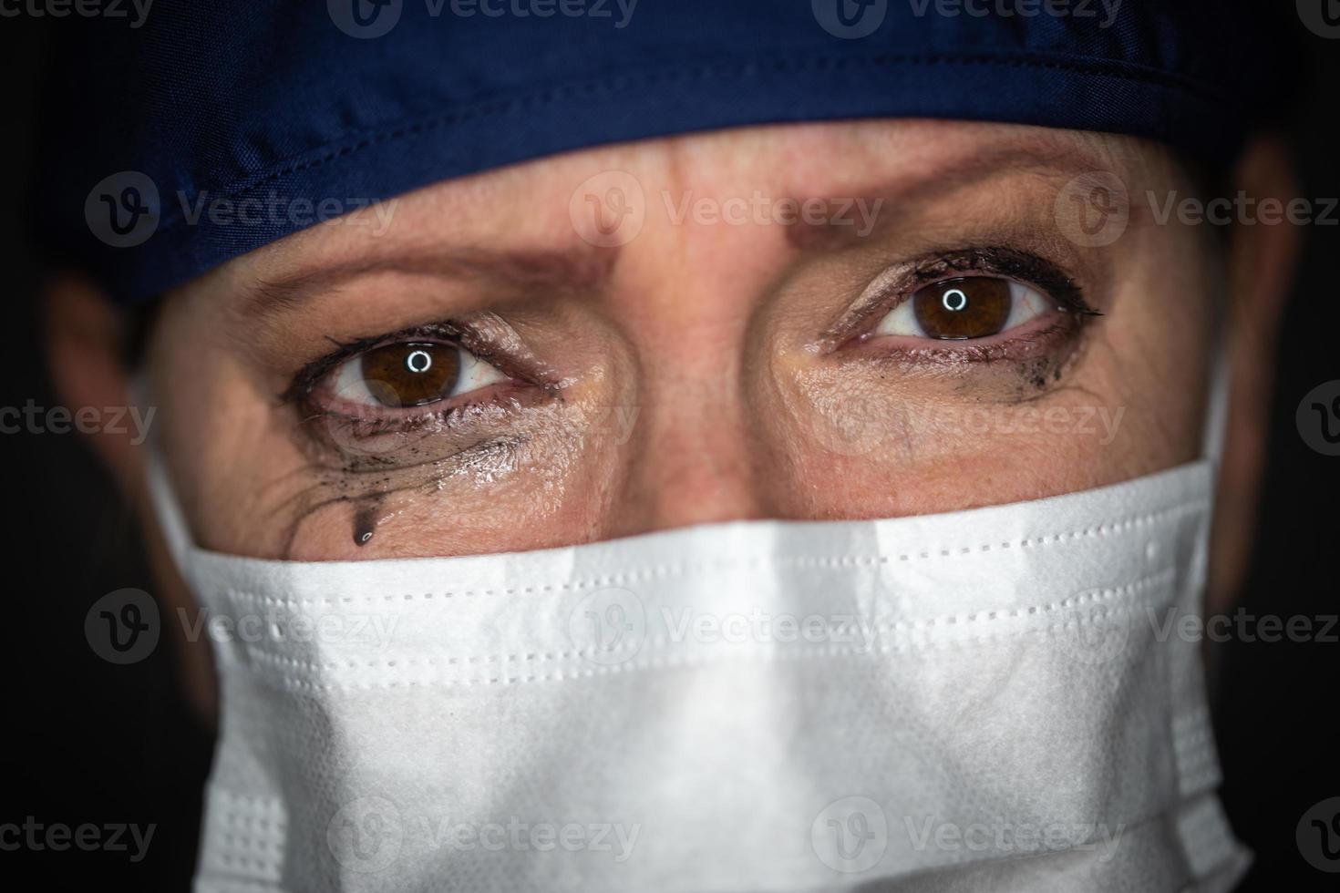 tårfylld betonade kvinna läkare eller sjuksköterska bär medicinsk ansikte mask på mörk bakgrund foto
