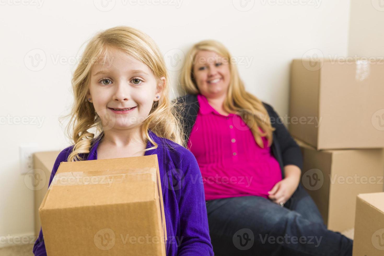 ung mor och dotter i tömma rum med rör på sig lådor foto