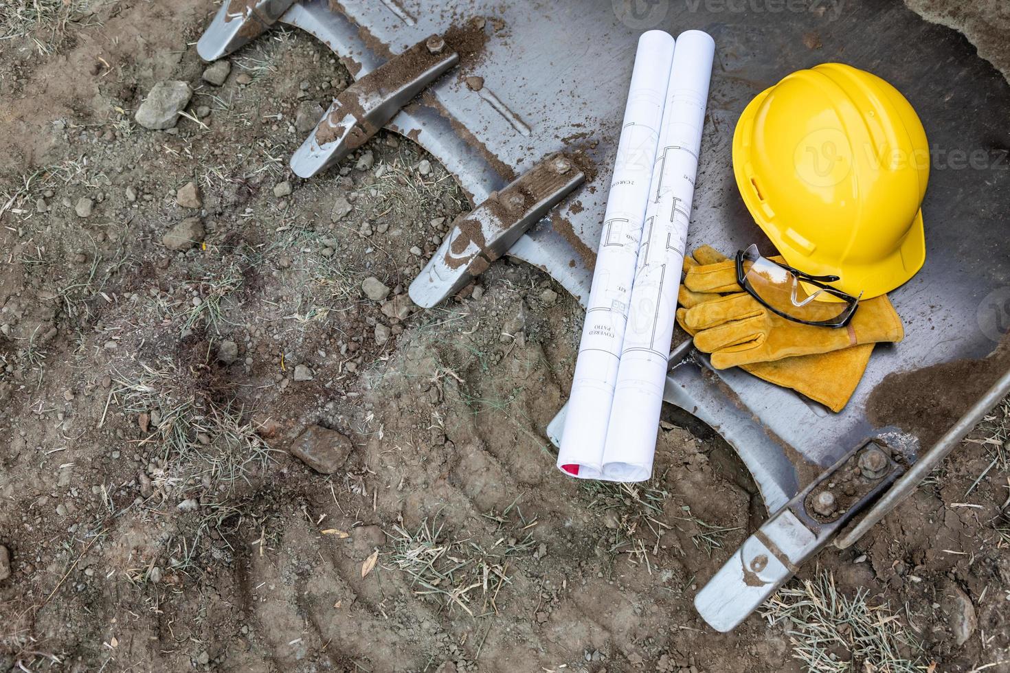 teknisk ritningar, hjälm, handskar och skyddande glasögon vilar på bulldozer hink abstrakt foto