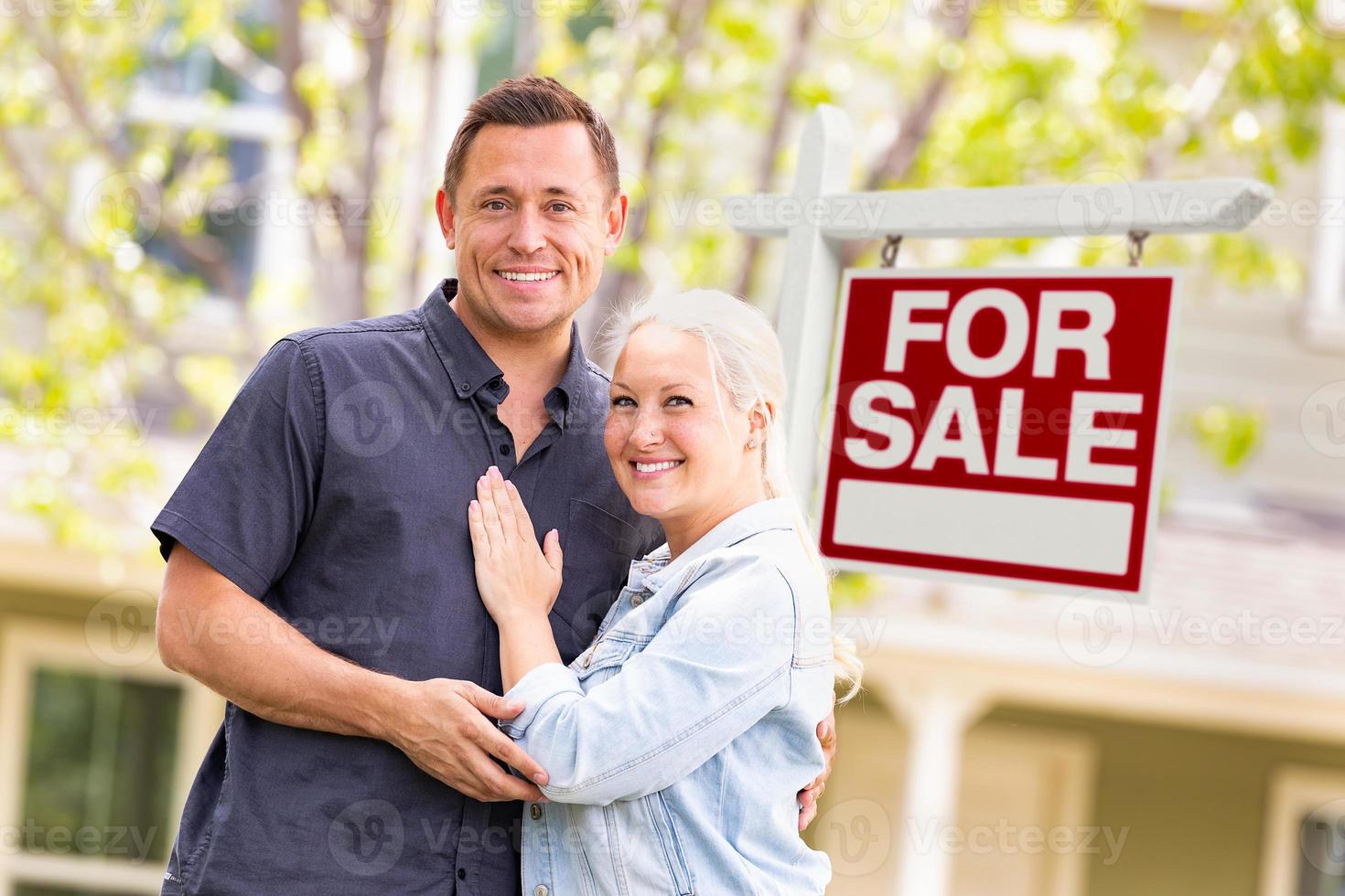 caucasian par i främre av för försäljning verklig egendom tecken och hus foto