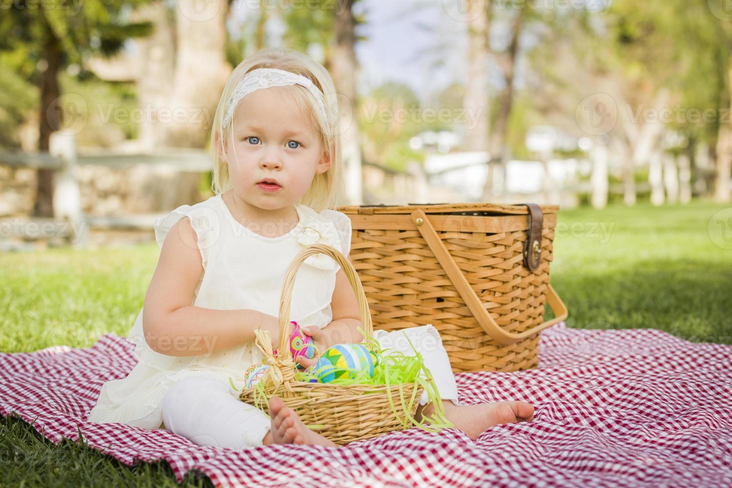 söt bebis flicka njuter henne påsk ägg på picknick filt foto