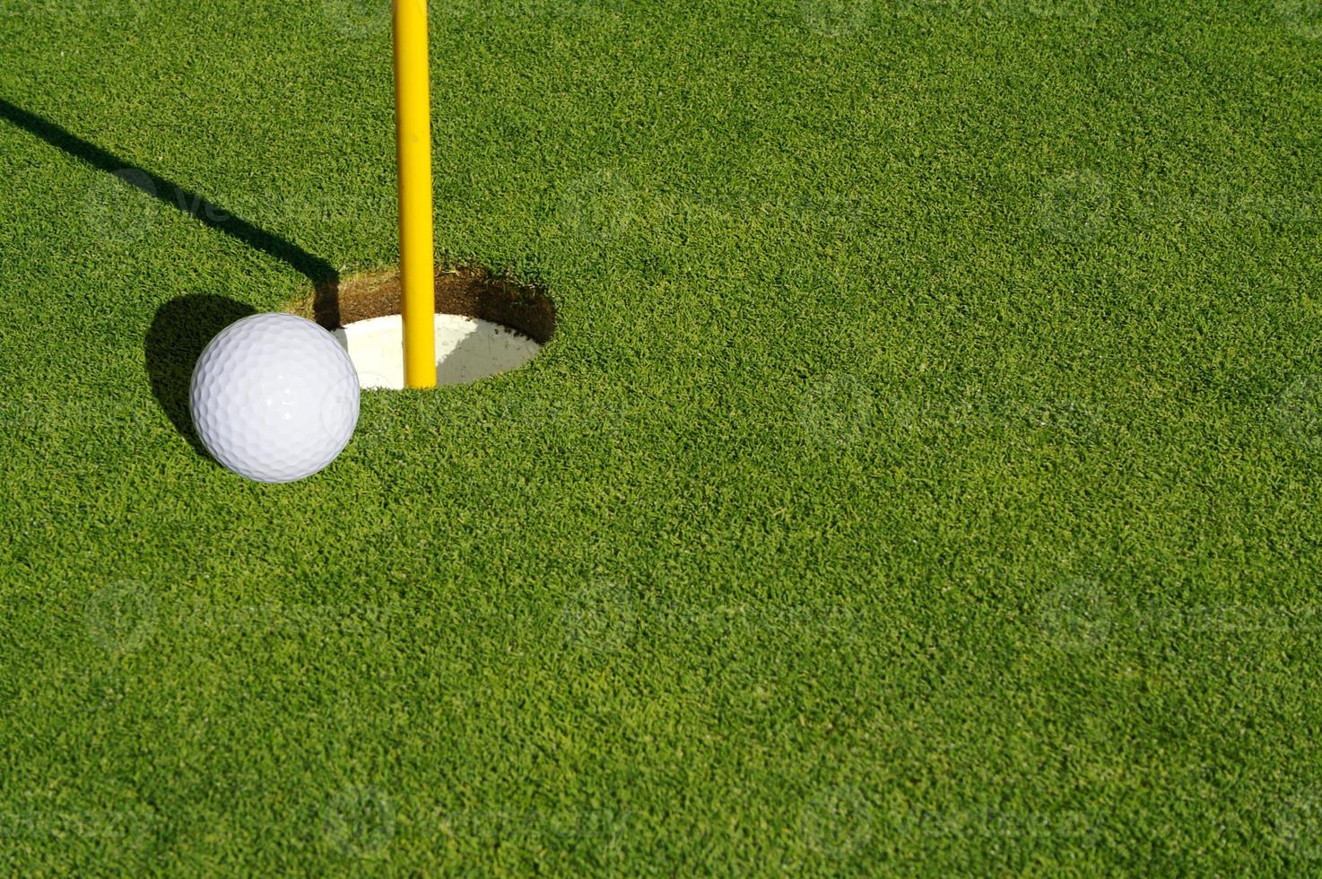 närbild av golf kurs grön, flagga stift och boll. foto