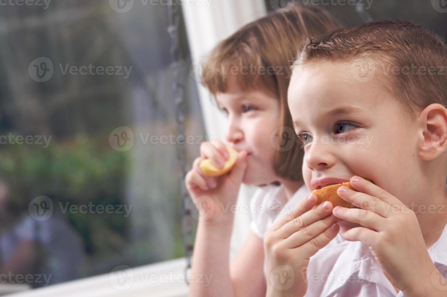 syster och bror äter ett äpple foto