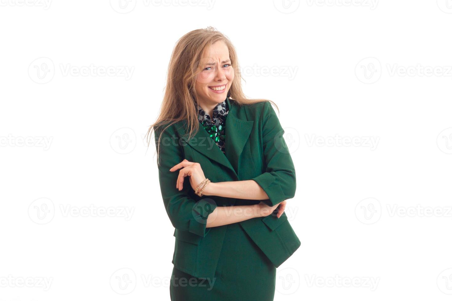 en charmig ung blond i grön jacka skrattar och håller händer nära de bröst foto
