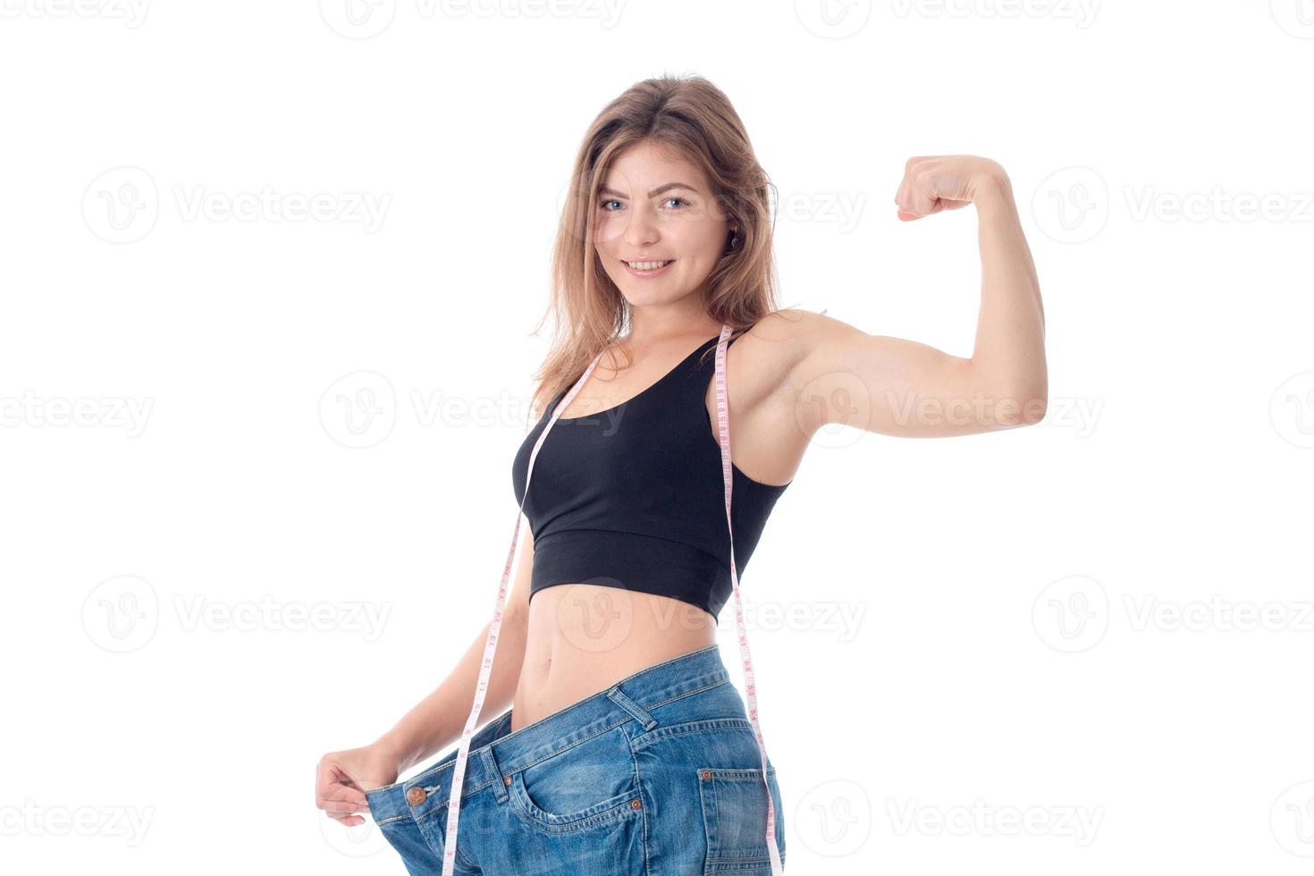 atletisk flicka i svart topp och de stor jeans visar biceps på hans ärm leende foto