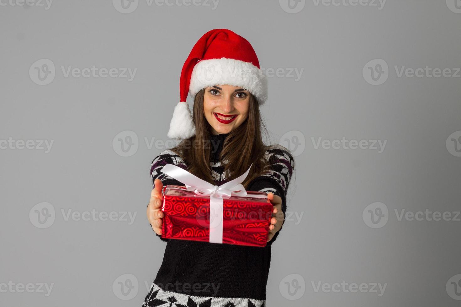 kvinna i värma Tröja och santa hatt med röd gåva foto