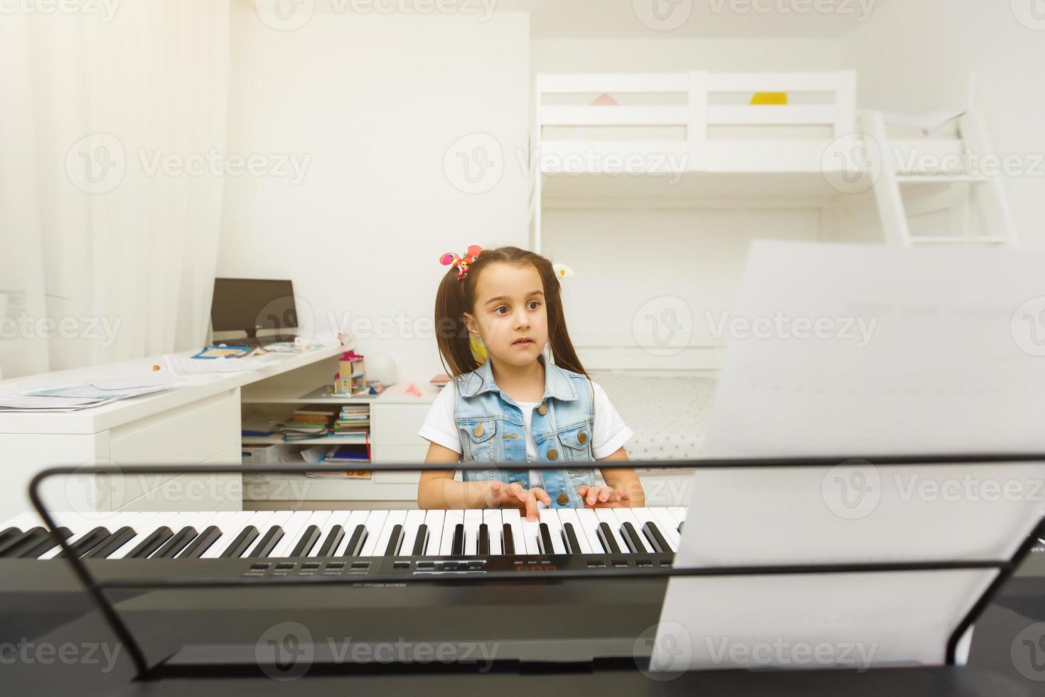 söt liten flicka spelar på piano, synthesizer. Träning. utbildning. skola. estetisk Träning. elementärt klassrum. foto