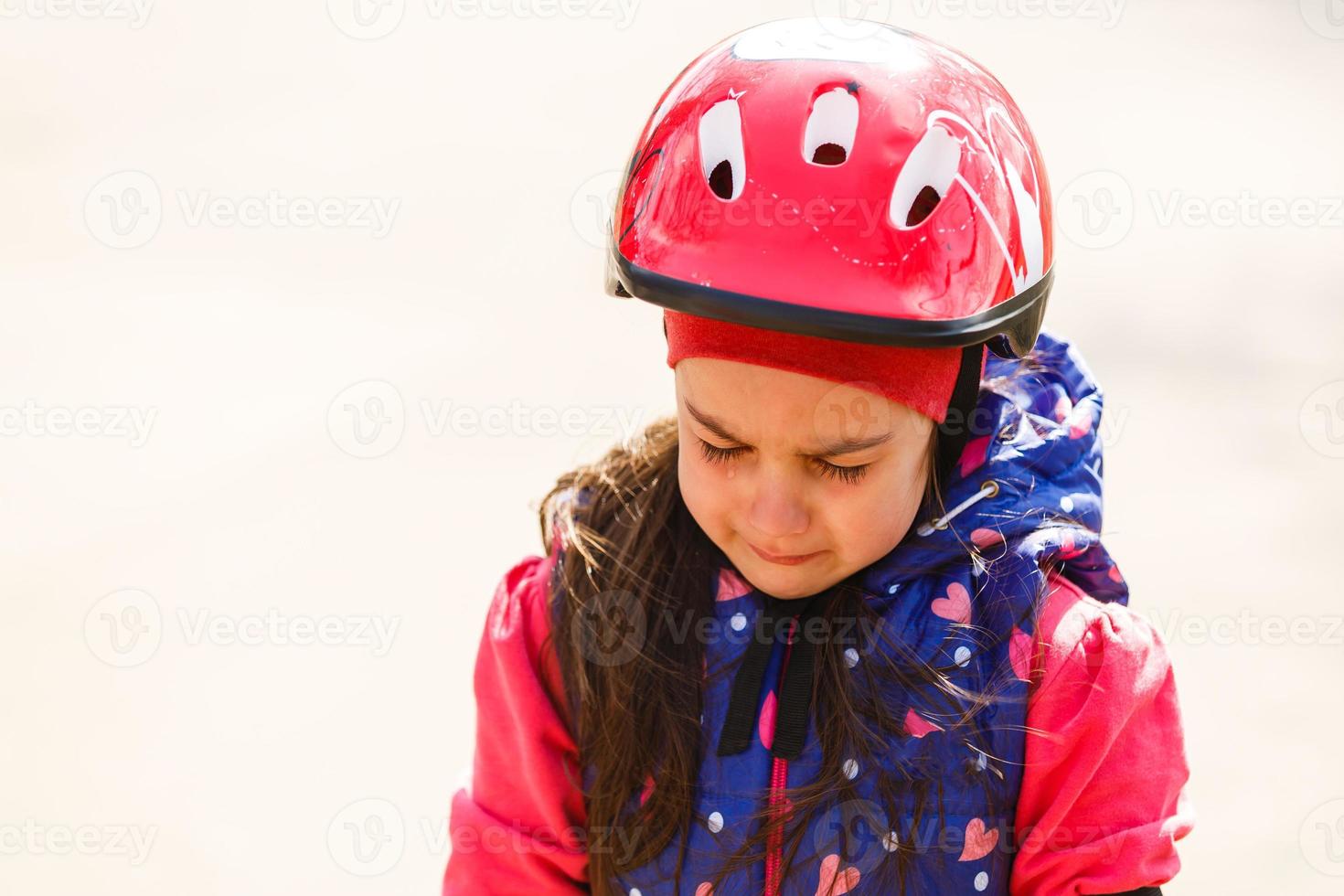 skön brunett liten flicka bär cykel hjälm och reflekterande väst med ledsen uttryck gråt. depression begrepp. foto