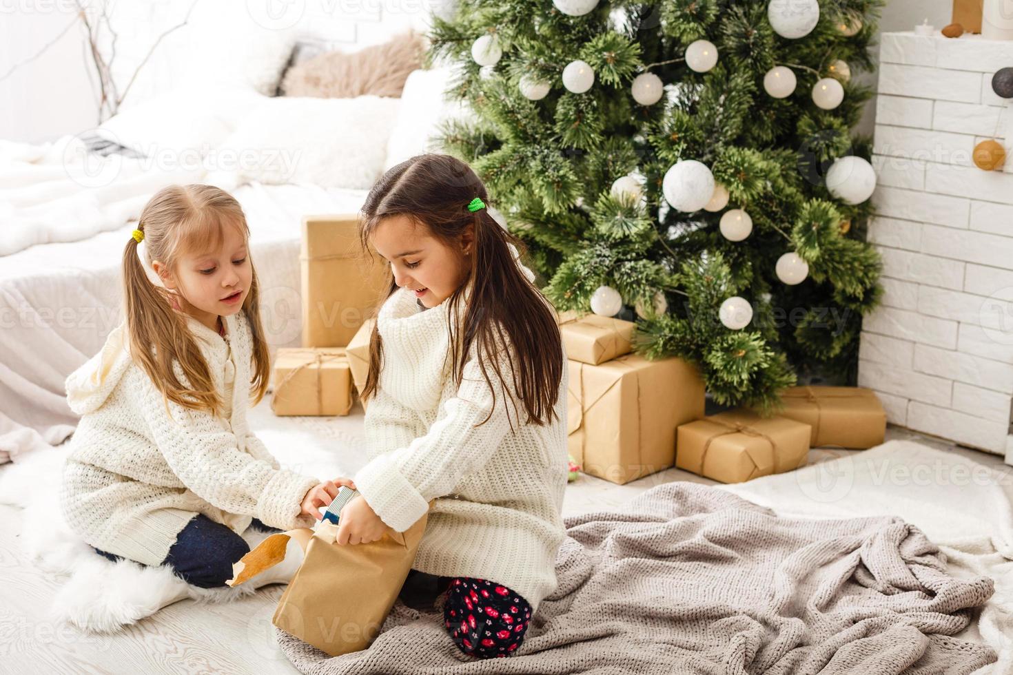 två liten flickor delning en överraskning på jul morgon- foto