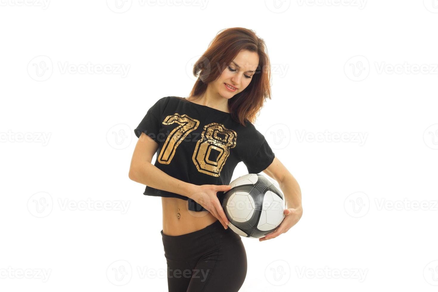 ljuv ung gymnast i svart t-shirt innehav en fotboll boll ser ner och leende foto