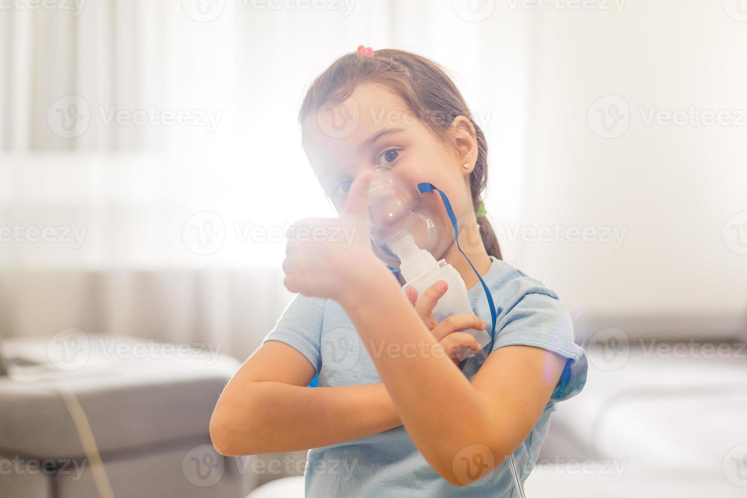 liten flicka i en mask, behandlingar respiratorisk tarmkanalen med en nebulisator på Hem foto