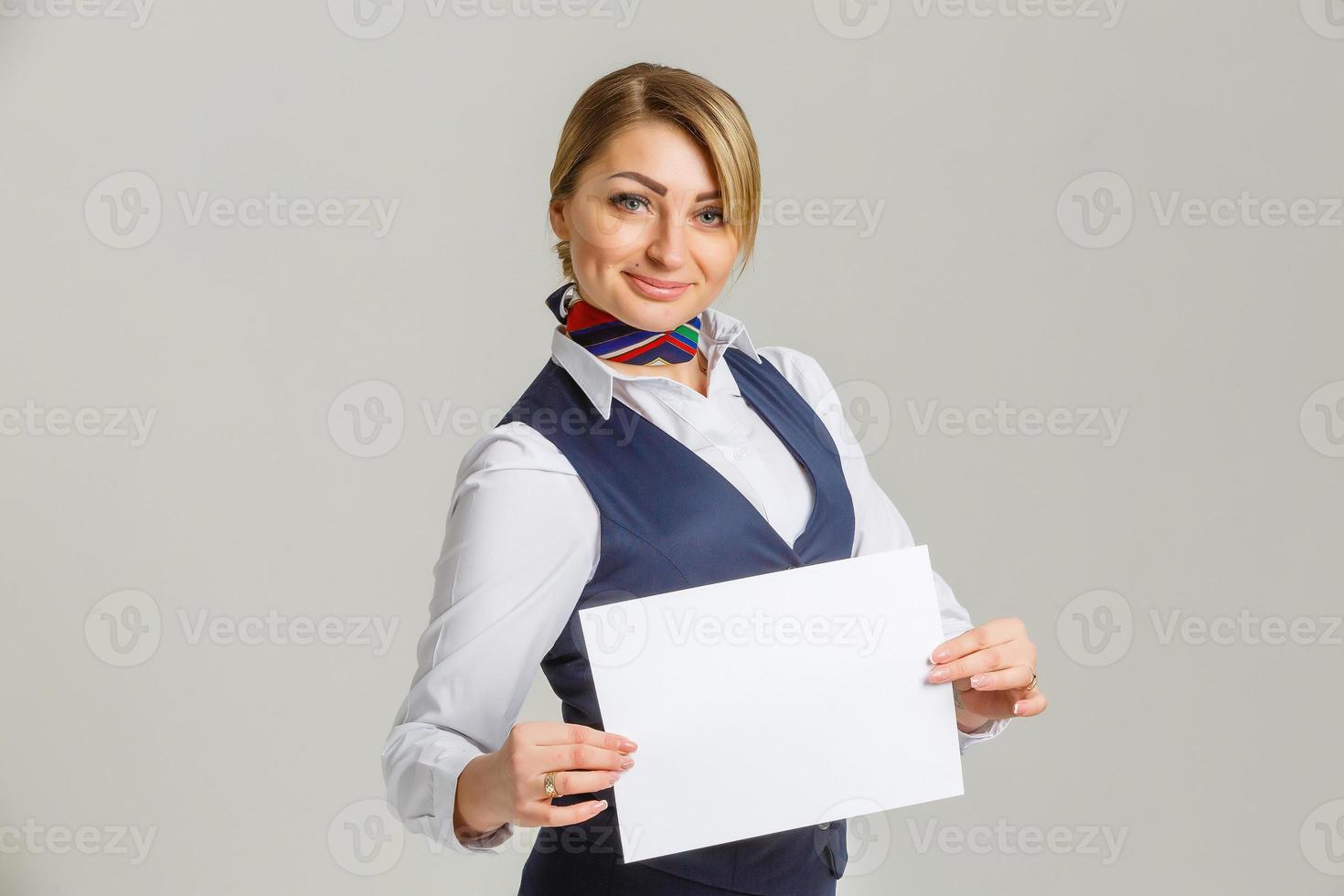 Söt Flygvärdinnan med en vit bit av papper i din händer foto