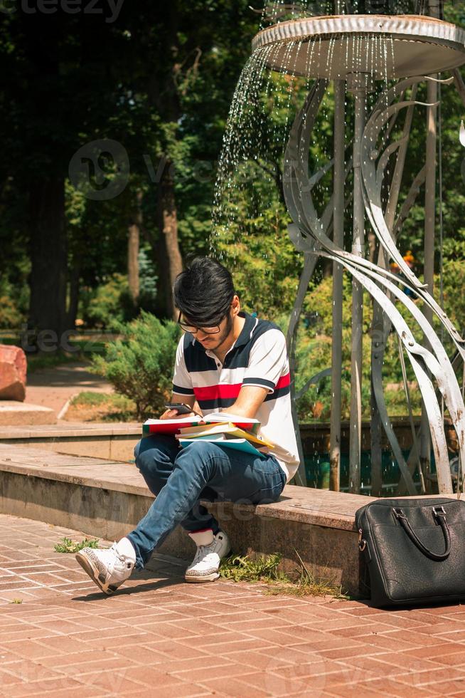 mode kille Sammanträde nära de fontän och läser böcker foto