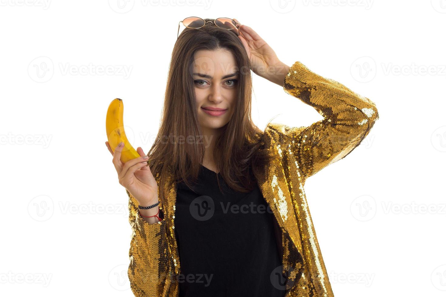 söt glamour kvinna i gyllene jacka med banan foto