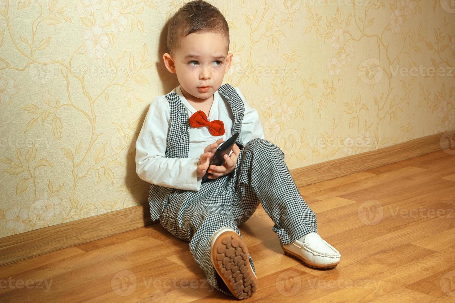 pojke sitter på de golv i elegant kostym foto